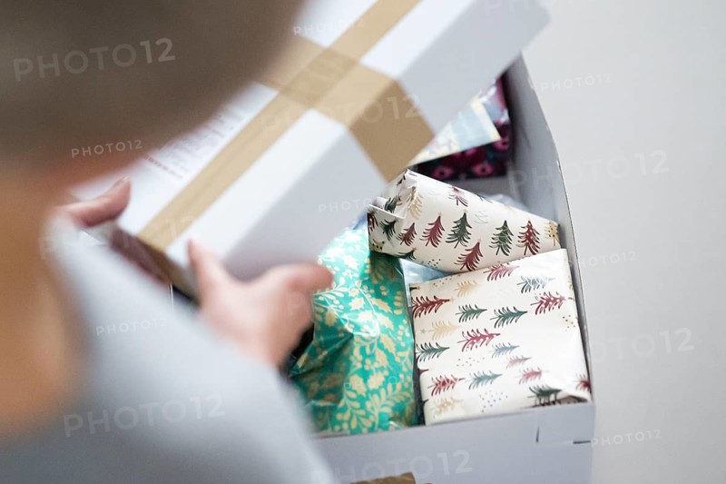 Symbolic photo on the subject of sending Christmas presents by post. A woman opens a parcel with Christmas presents. Berlin