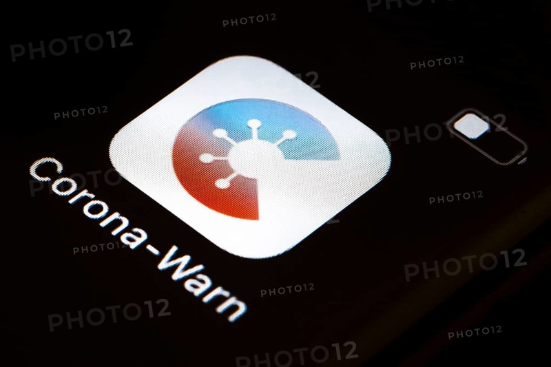The Corona warning app is displayed on the screen of a smartphone. The app is designed to help trace and interrupt chains of infection of SARS-CoV-2