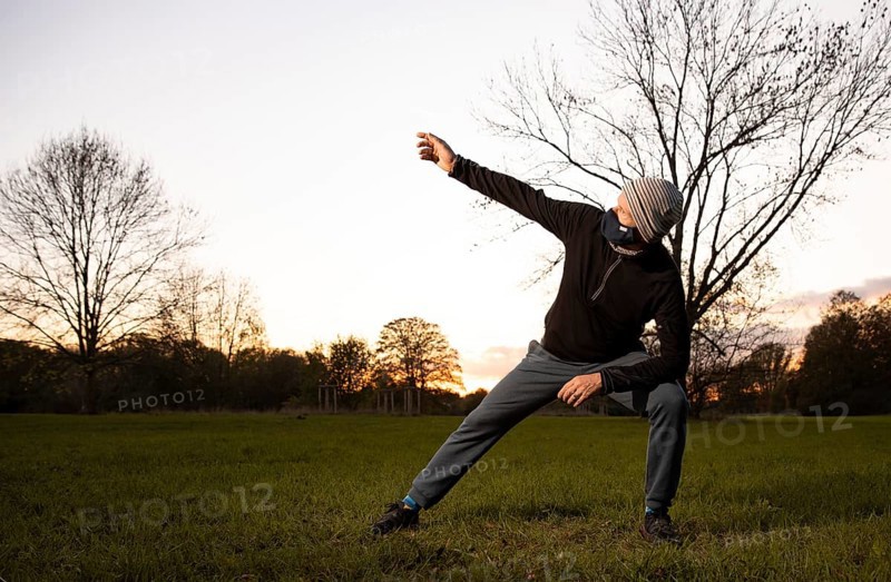 Man with mask stretches in a meadow in autumn.
