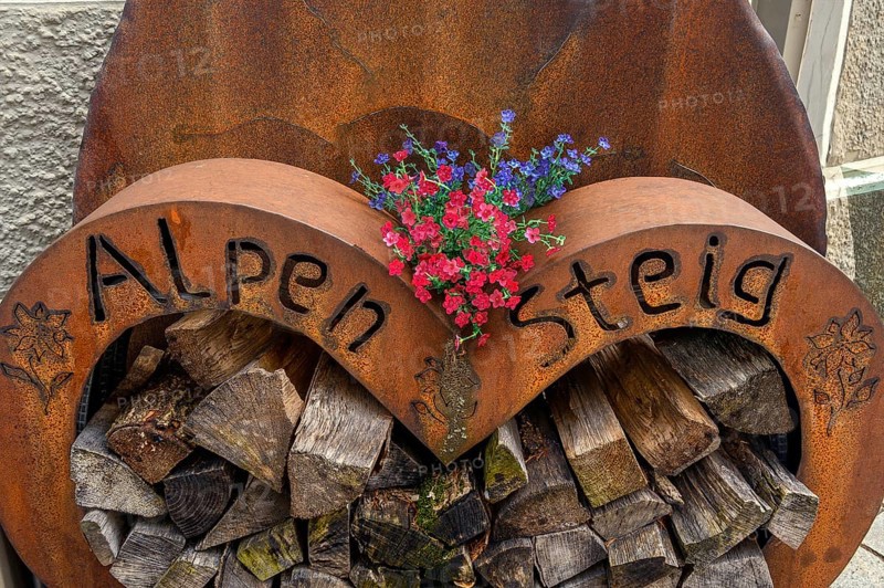 Iron storage container with firewood and geraniums