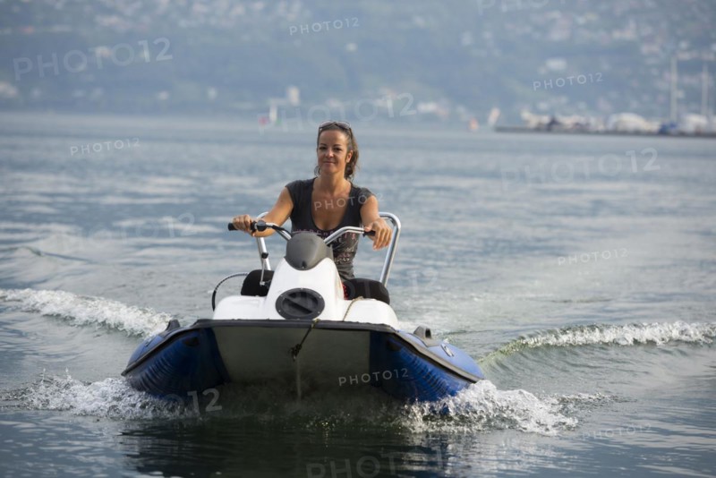Happy woman driving a boat on the water