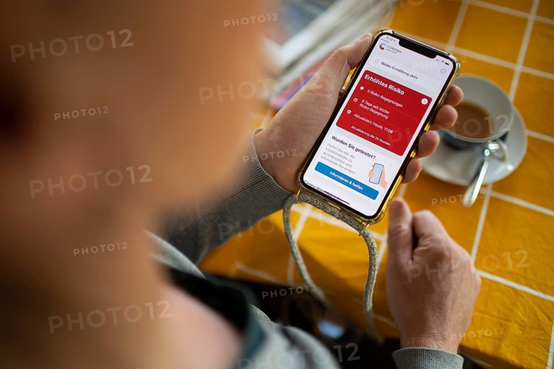 Corona Warnapp. Person looks at the Corona Warnapp indicating 3 risk encounters.