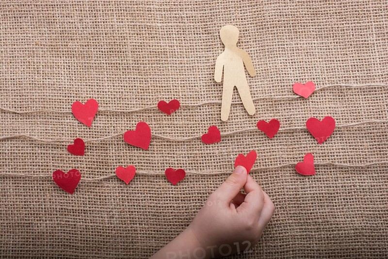 Paper man and heart icons on linen threads on canvas
