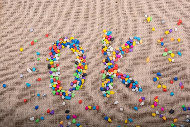 Colorful pebbles form the word OK on canvas ground