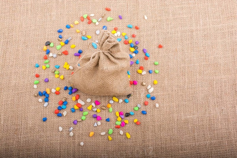 Little sack amid colorful pebbles spread on canvas