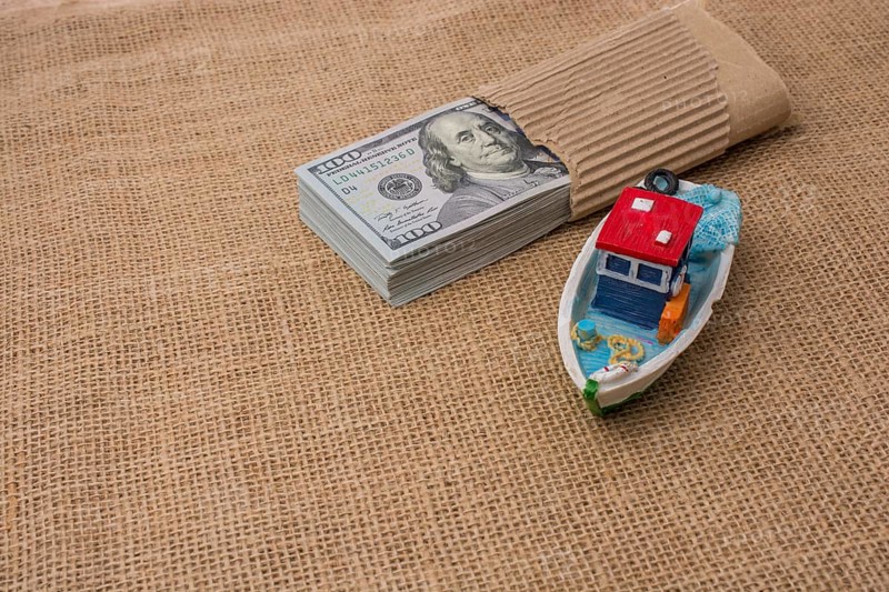 Model boat and banknote bundle of US dollar on canvas