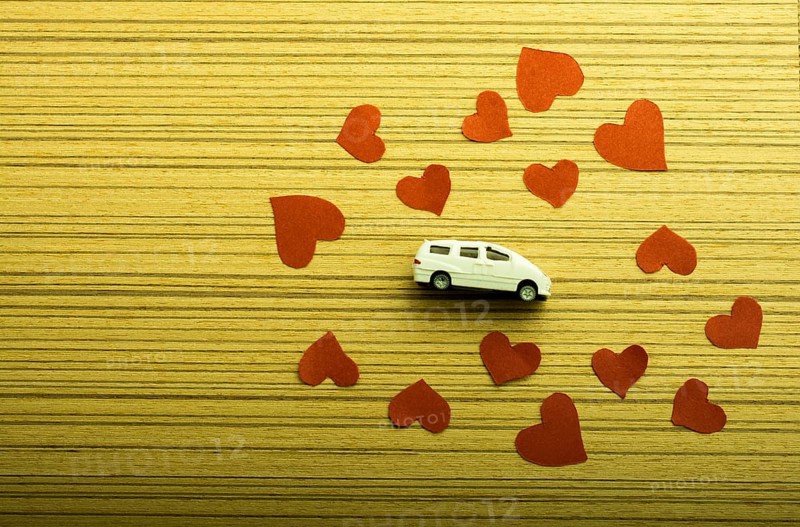 Love concept with model car and heart shaped papers