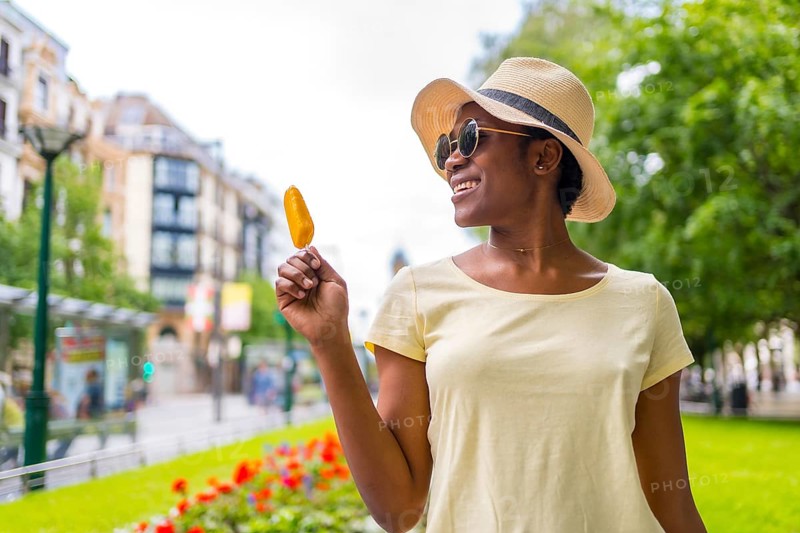 African black ethnicity woman eating a mango ice cream in the city