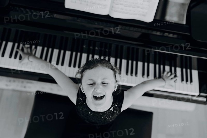 Elegant girl sits at the concert grand and plays the piano