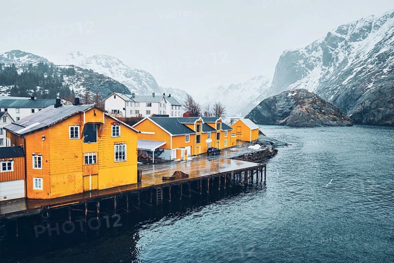 Panorama of Nusfjord authentic fishing village with yellow rorbu houses in Norwegian fjord in winter. Lofoten islands