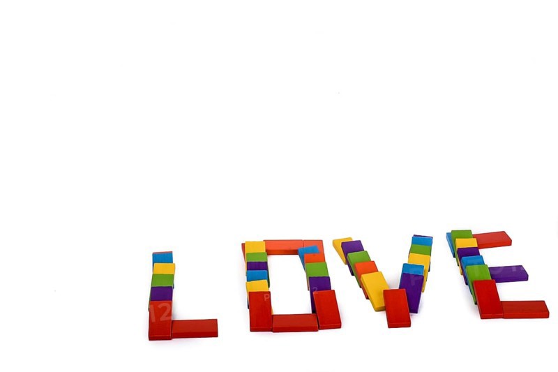 Colorful wooden dominos write the word love on a white background