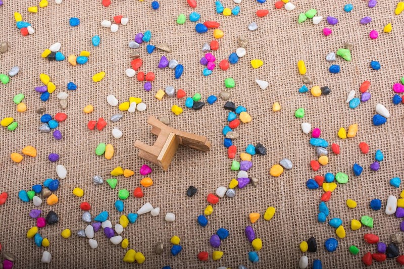 Little chair amid pebbles on canvas background