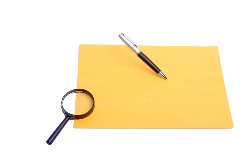 Pen and magnifying glass placed on yellow paper