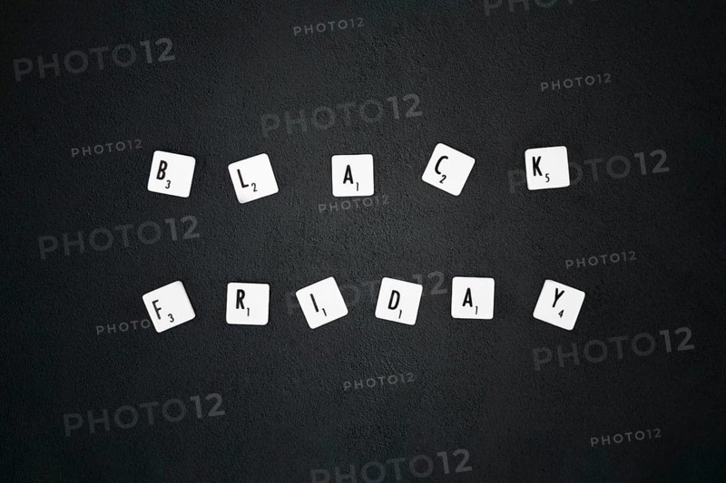 Black friday composition. Text on board game chips. Black textured background