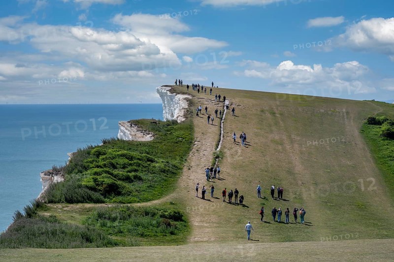 Tourists walking along the chalk cliffs at Beachy Head