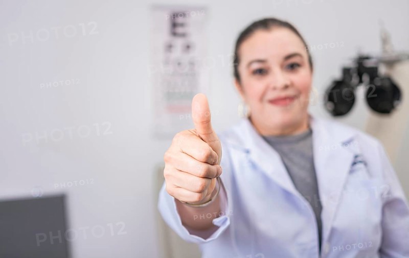 Female optometrist with thumb up in the laboratory. Optometry specialist with thumb up. Smiling eye doctor with thumb up in office