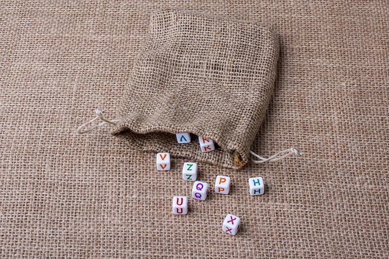 Colorful alphabet letter cubes out of sack on a canvas