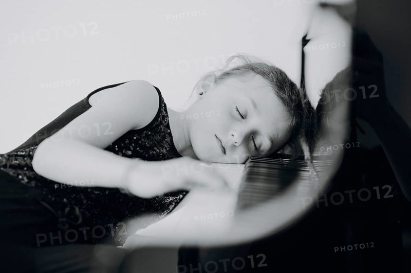 Elegant girl sits at the concert grand and plays the piano