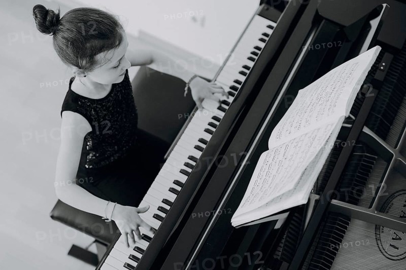 Elegant girl sits at the concert grand and plays the piano