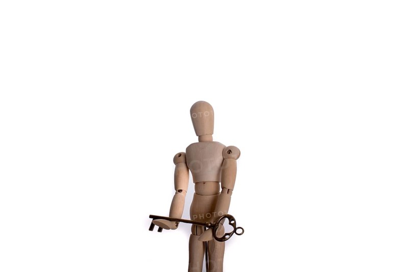 Puppet holding an antique golden key in hand on a white background