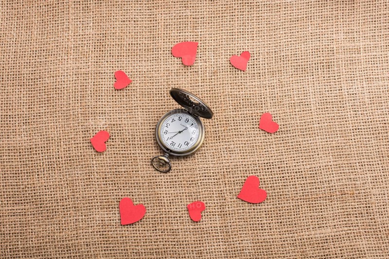 Love concept with pocket watch and paper hearts on threads