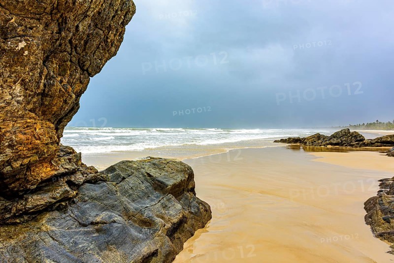 Deserted beach with coconut trees and rocks on a rainy day in Serra Grande on the coast of Bahia