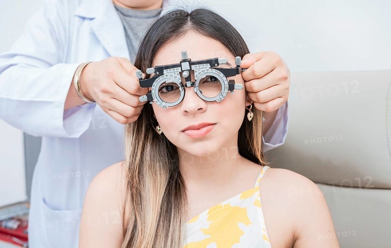 Hands of optometrist examining patient with optometrist trial frame. Young patient with optometrist trial frame
