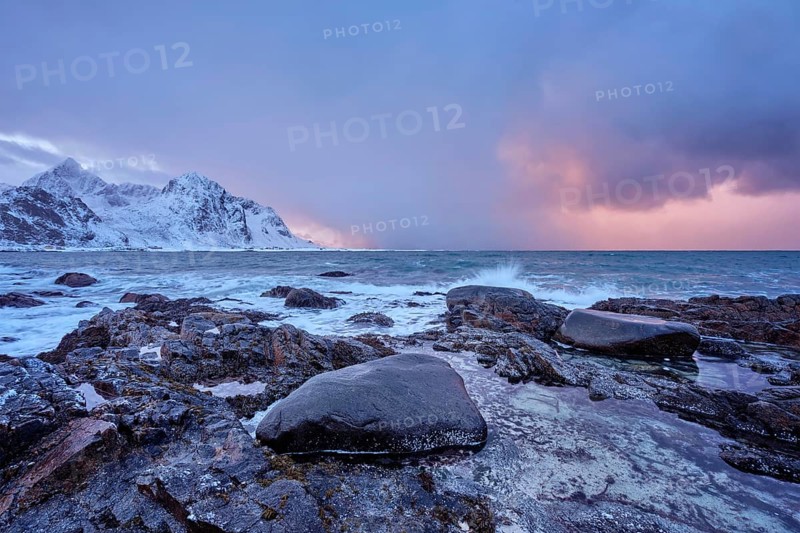 Beach of Norwegian sea on rocky coast in fjord on sunset in winter. Vareid beach