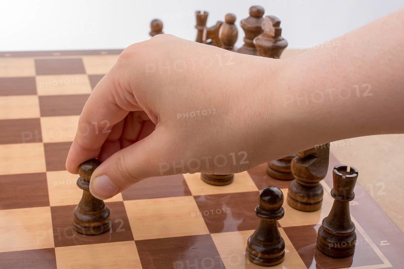 Person playing chess game making a move on board