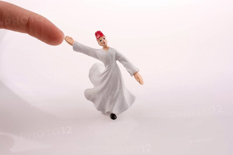 Hand holding a Sufi Dervis on a white background