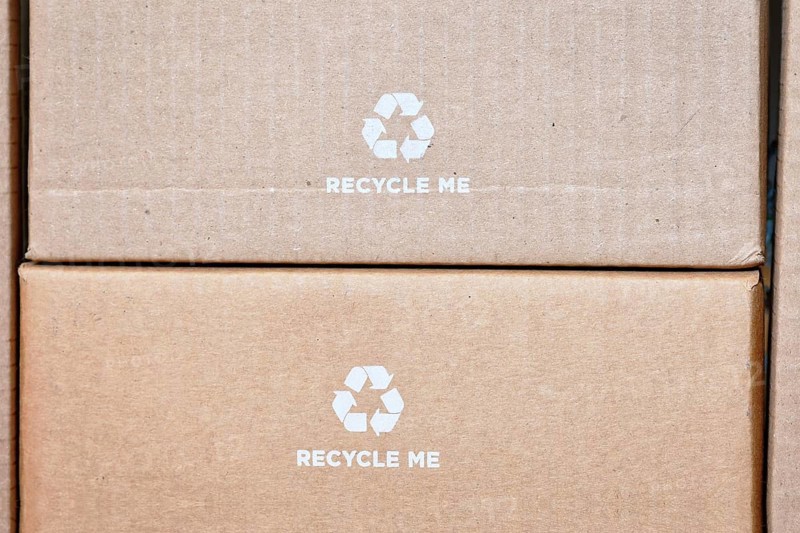 Cardboard boxes with recycling arrow symbol and text saying Recycle me