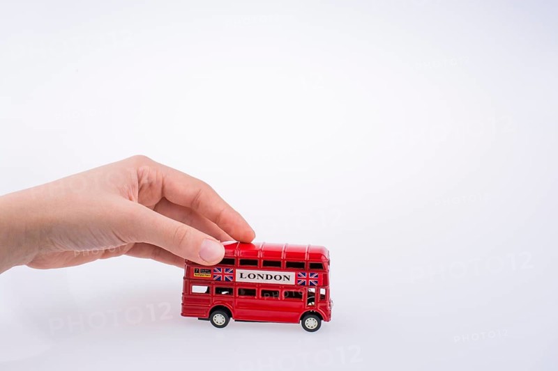Child hand playing with London double decker bus model on white background
