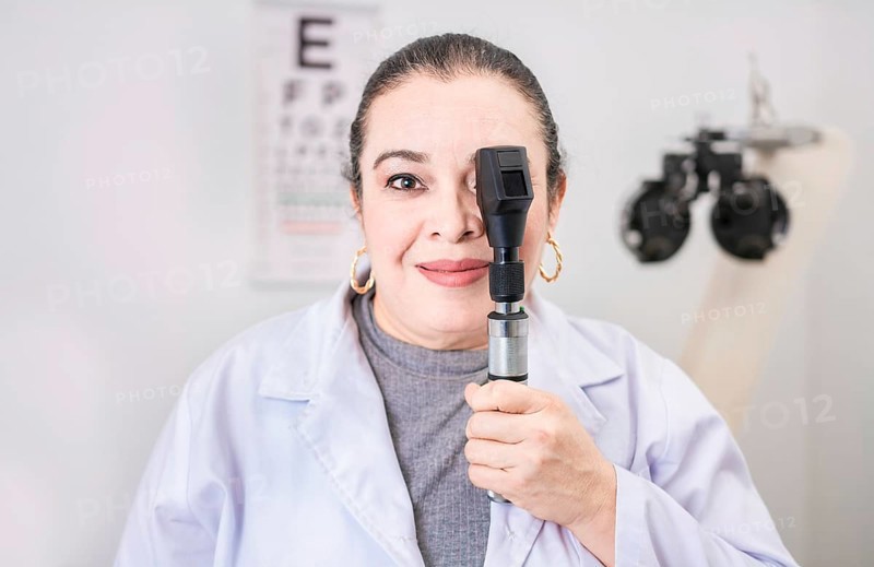 Portrait of female optometrist with ophthalmoscope in the laboratory. Smiling oculist holding an ophthalmoscope in the laboratory