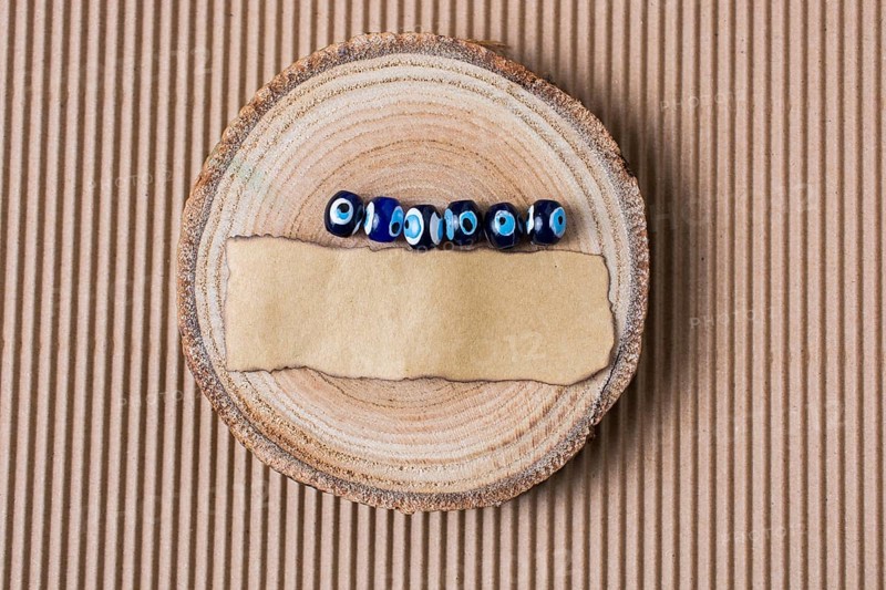 Evil eye beads and piece of burnt paper on wood log