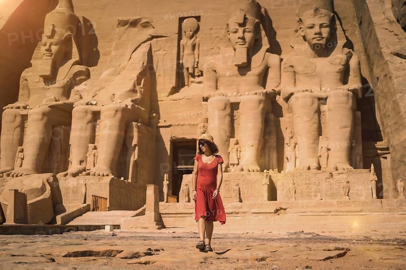 A young tourist in a red dress leaving the Abu Simbel Temple in southern Egypt in Nubia next to Lake Nasser. Temple of Pharaoh Ramses II