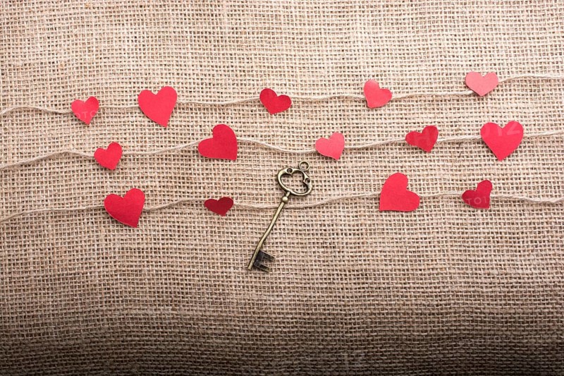 Love concept with heart shaped papers and key on linen threads