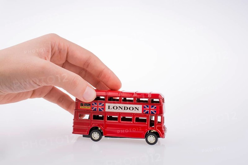 Child hand playing with London double decker bus model on white background