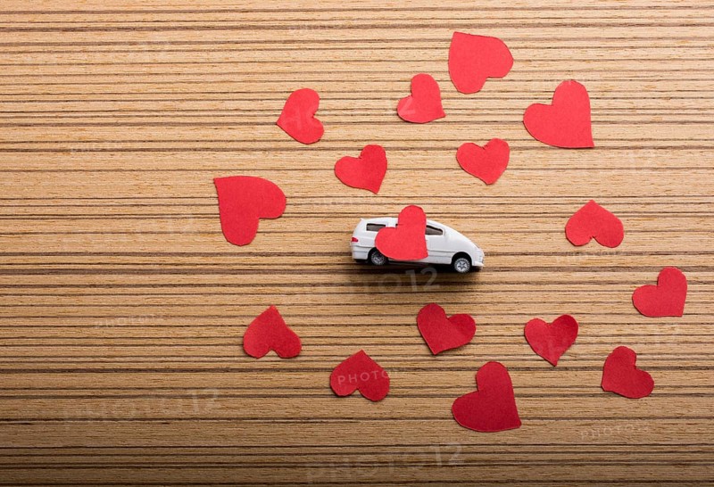 Love concept with model car and heart shaped papers
