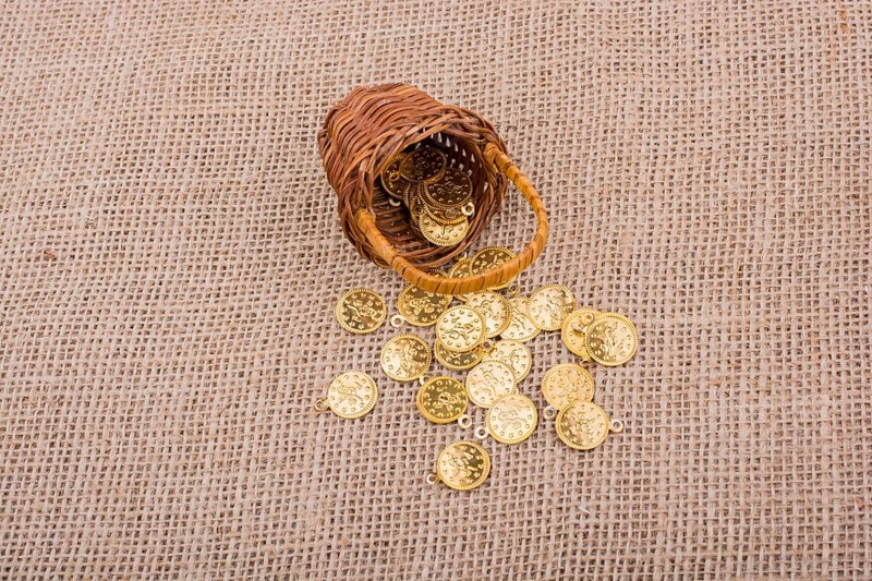 Fake gold coins out of a little basket on canvas
