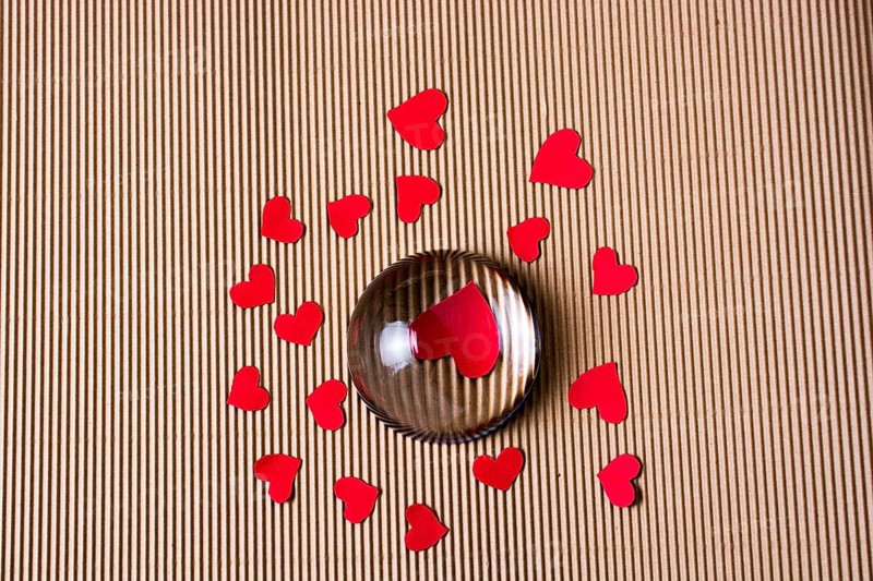 Red color paper hearts under and around half glass globe