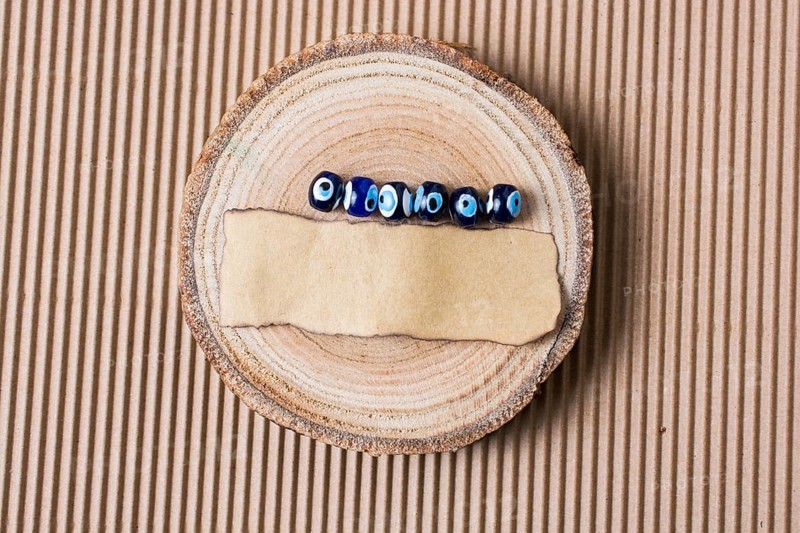 Evil eye beads and piece of burnt paper on wood log