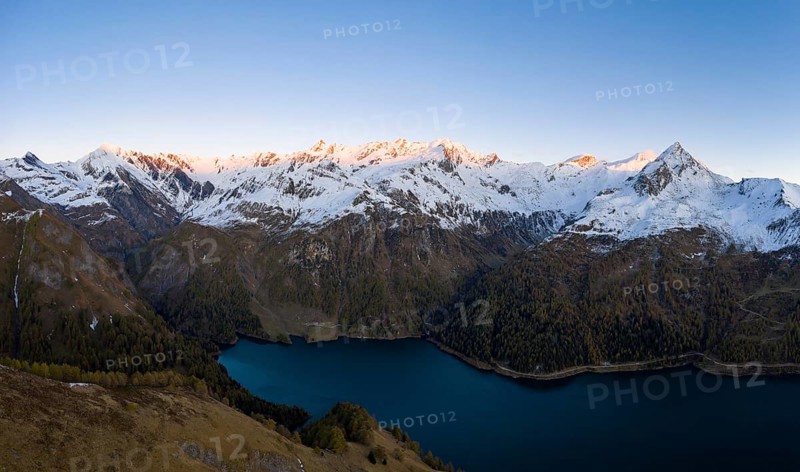 Aerial view over Lago di Luzzone with the first sunlight on the mountain peaks