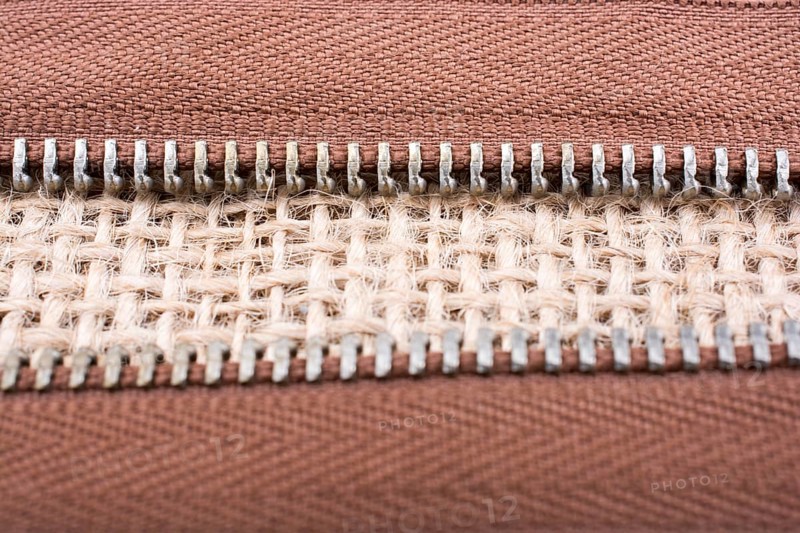 Parts of the brown color zipper on linen canvas background