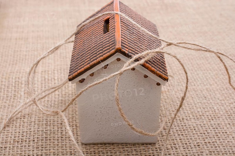 Thread wrapped around a model house on a brown background