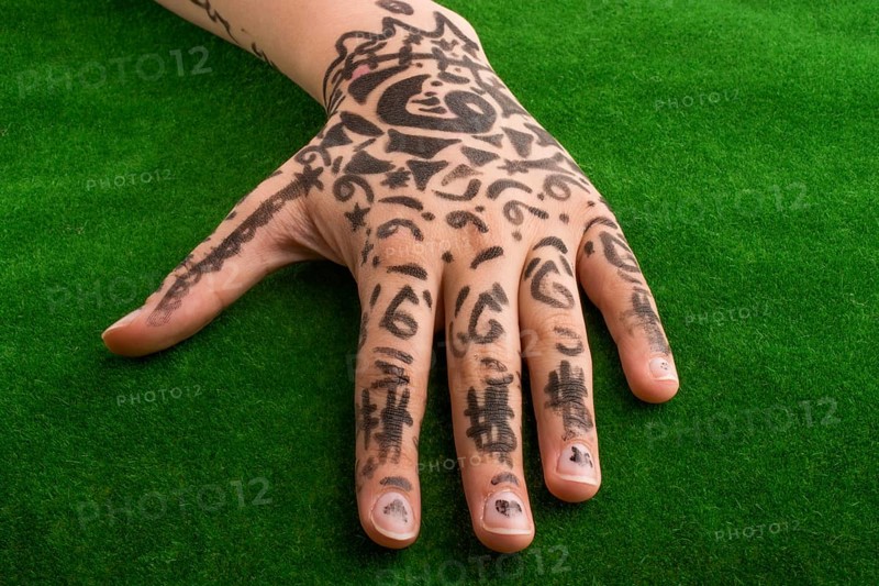 Hand with tattoo on green grass