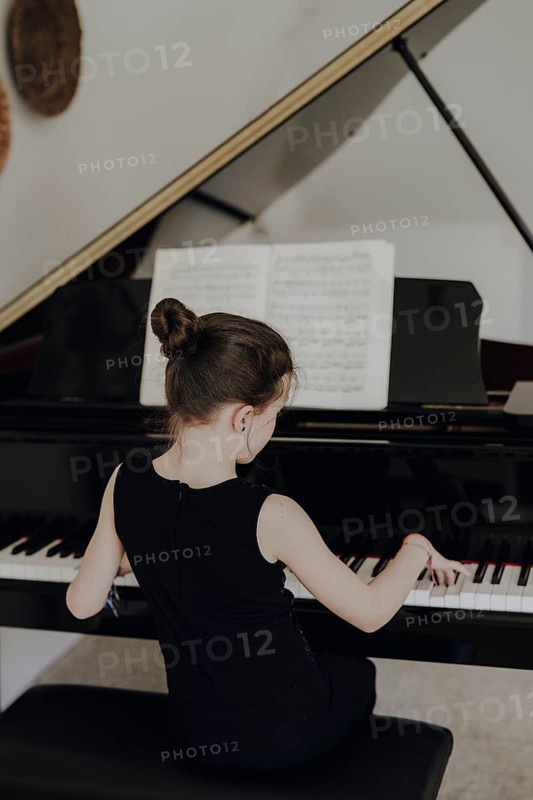 Elegant girl sits at the concert grand and plays the piano