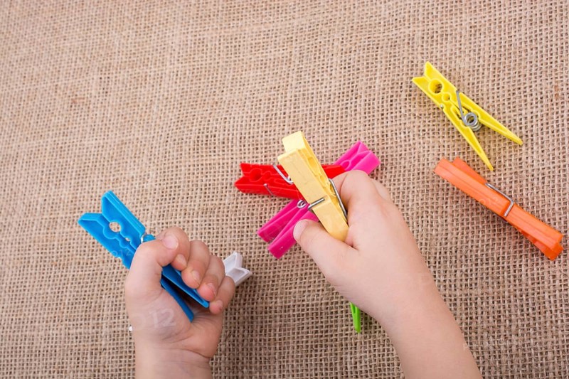 Color clothespin in hand on a linen canvas background