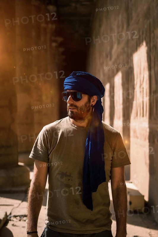 A young tourist in a blue turban visiting the Edfu Temple in the morning near Aswan city. Egypt