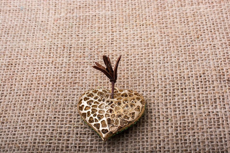 Heart shaped gold color metal object on canvas