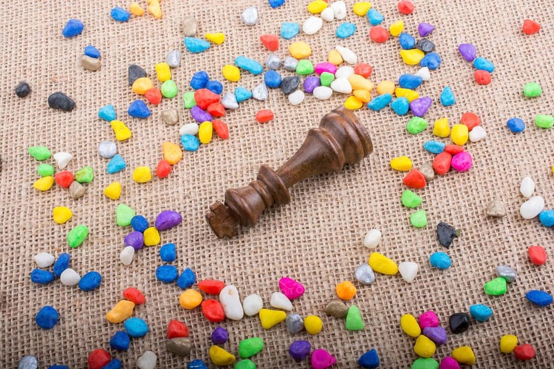 Chess king amid colorful pebbles on canvas background